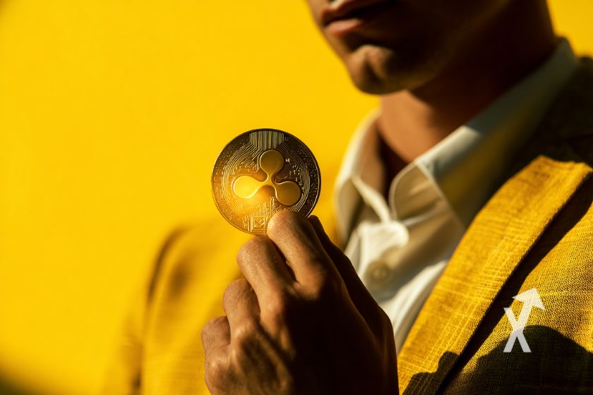 Homme en costume sur un fond jaune qui tient un jeton XRP en jaune