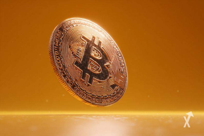 Une pièce de Bitcoin géante sur un fond orange