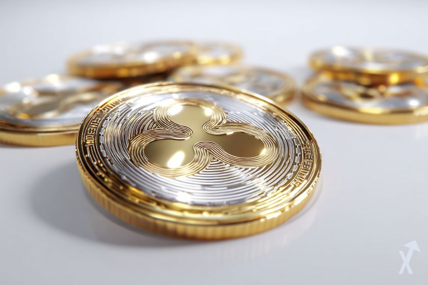 coin 3D xrp doré au milieu d'autres coins crypto, sur fond gris clair