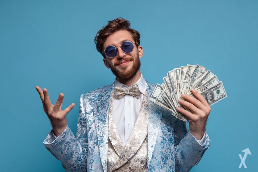 trader en costume souriant, avec des billets de dollars sur fond bleu