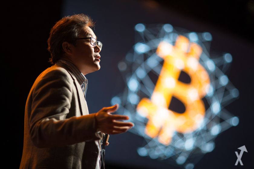 tom lee parlant du bitcoin lors d'une conférence, logo bitcoin en fond