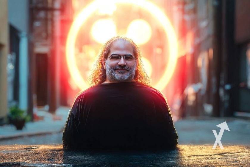 David Shwartz sur un fond gris avec logo orange lumineux du XRP derrière
